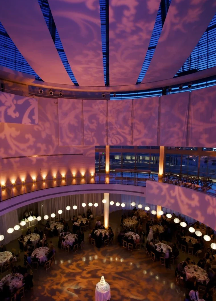 Dinner tables on the Rotunda floor seen from above, with patterned light across the walls